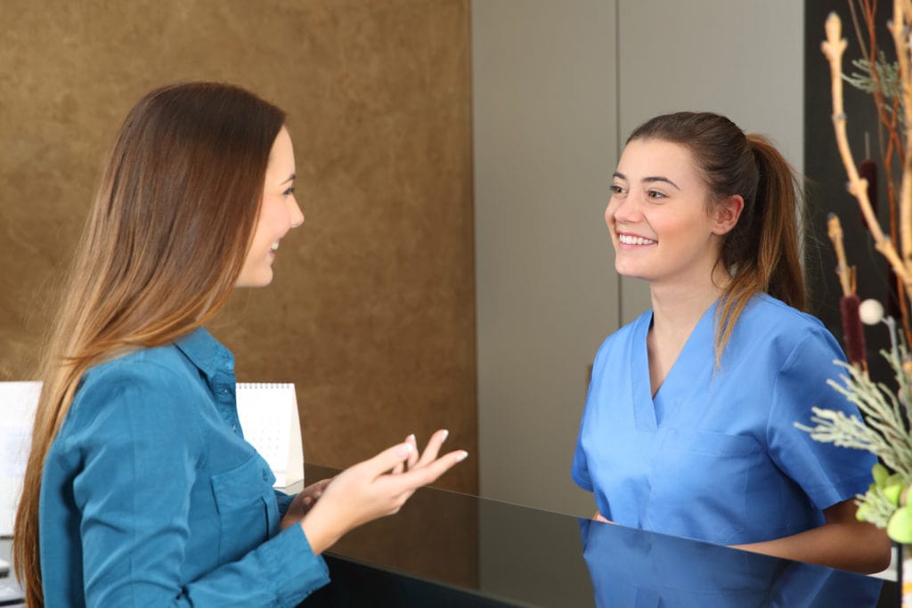 Nurse attending patient in a reception desk Prism Career Institute