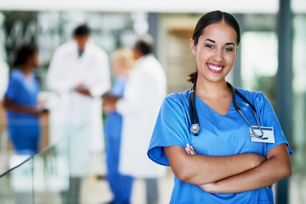 Portrait of a healthcare worker standing in a hospital with colleagues in the background